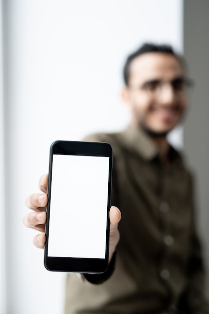 Smartphone con touchscreen vuoto in mano del giovane uomo d'affari contemporaneo in piedi davanti alla telecamera