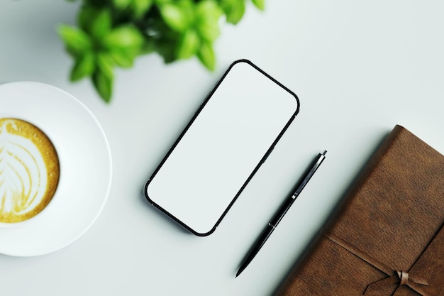 Фото Смартфон с пустым белым экраном с ноутбуком для кофейной чашки и комнатным растением на белом столе
