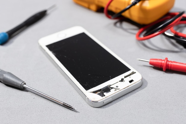 Smartphone with broken screen on electronic store workbench Repairing damaged mobile phone concept