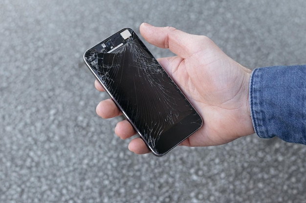 Photo smartphone with a broken screen glass in hand of young man