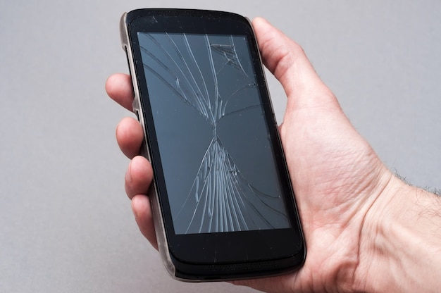 Smartphone with broken screen in hand