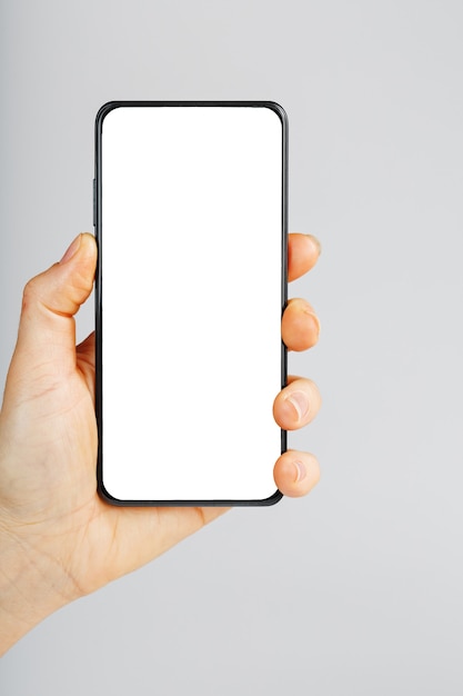 Smartphone with a clean white screen in your hand close-up. Free space