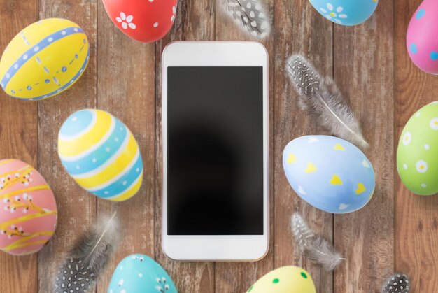 Foto smartphone con uova di pasqua e piume di quaglia