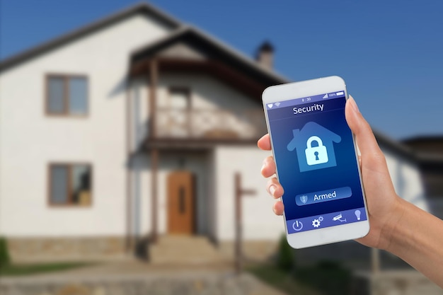 Smartphone with home security app in a hand on the building background