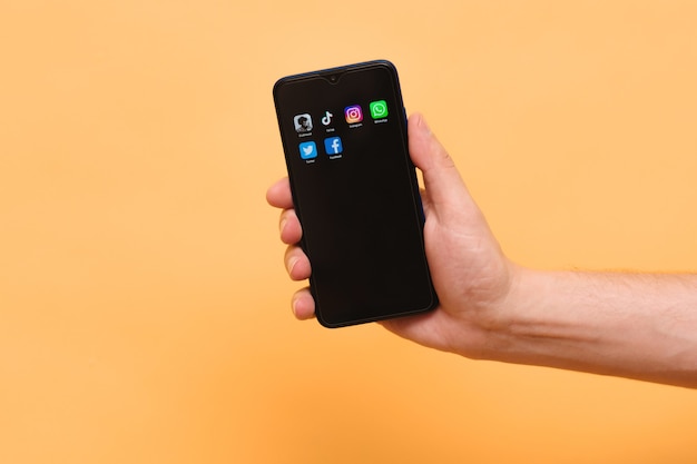 smartphone with icons of trending social media apps in a man's hand