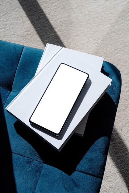 Photo smartphone with isolated screen on blue chair for mockup design at home interior