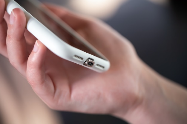 Smartphone with a magnetic connecting cable close-up in female hands.