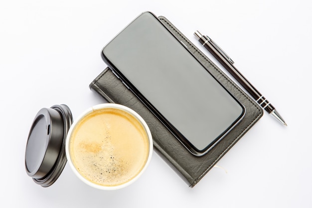 Smartphone with note pad and cup of strong coffee