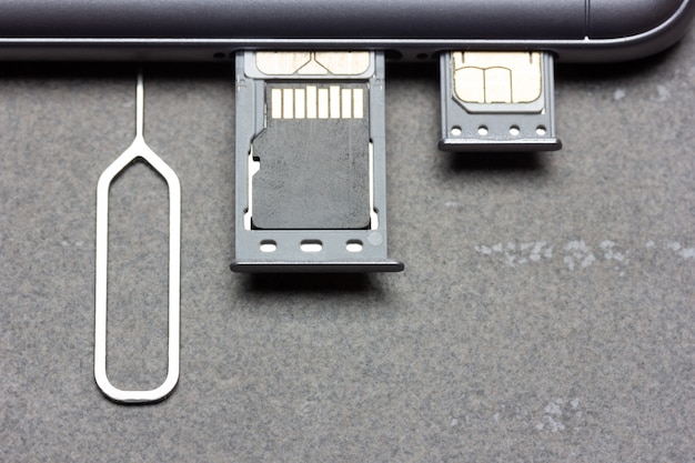 Смартфон с открытыми слотами для SIM-карт и памятью Micro SD на сером фоне