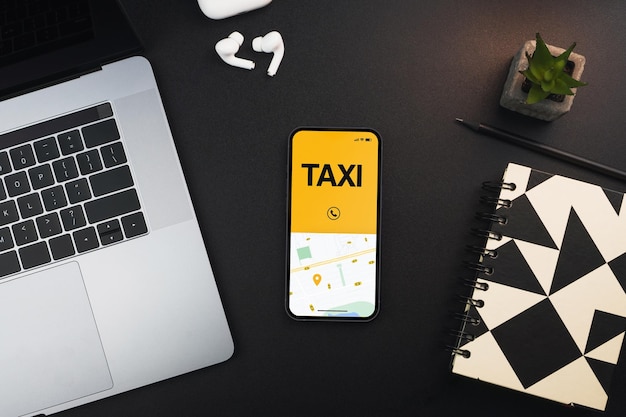 Smartphone with Taxi Service app on the screen on black background table. Office environment. Mobility service provider worldwide.