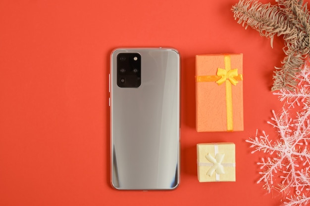 写真 3つのカメラと赤い背景の上のクリスマスの装飾とスマートフォン