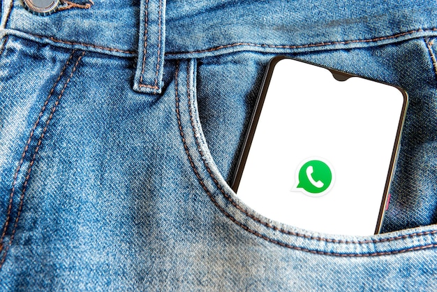 Смартфон с приложением WhatsApp в кармане джинсов