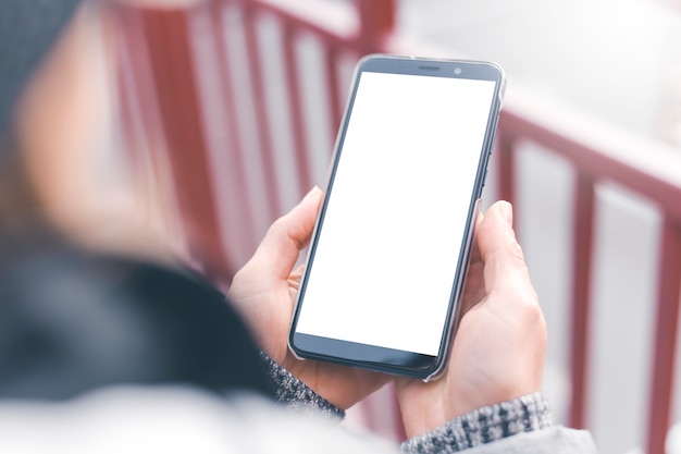 Smartphone in with a white screen in the hands of a girl.