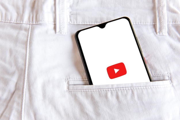 写真 ホワイトジーンズのポケットにyoutubeアプリケーションを搭載したスマートフォン