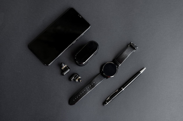 Smartwatch en telefoon met pen en koptelefoon op een monochromatische achtergrond