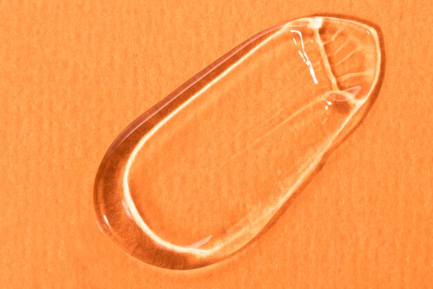 Smear of a gel transparent cosmetic product closeup on an orange background top view Moisturizer