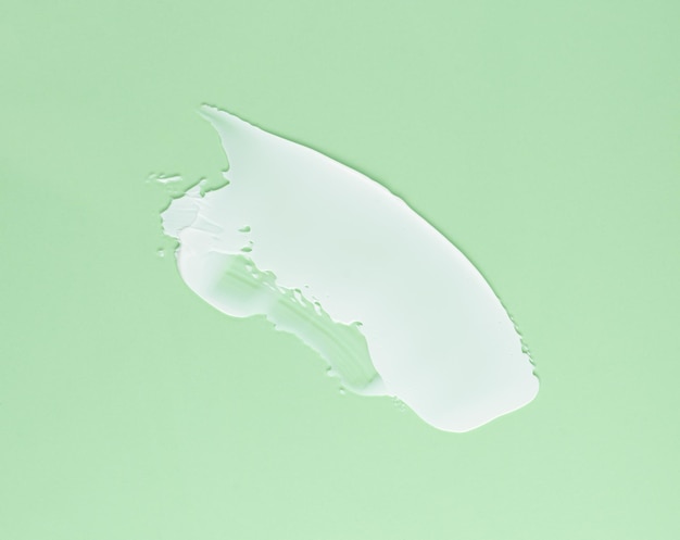 Photo smear of white cream for face and body on a green background