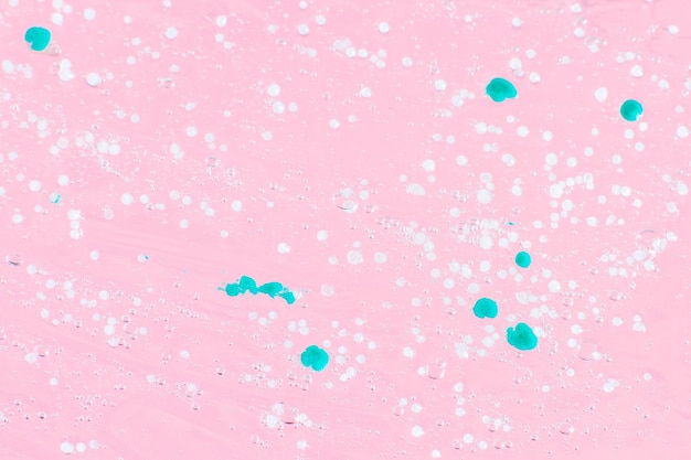 Smeared transparent gel with blue granules On a pink background