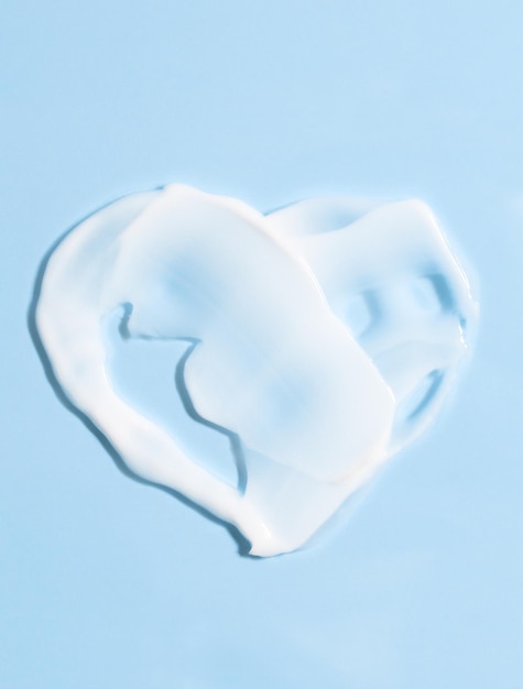 Smears of cream on a blue background in the shape of a heart white cosmetic texture for skin care