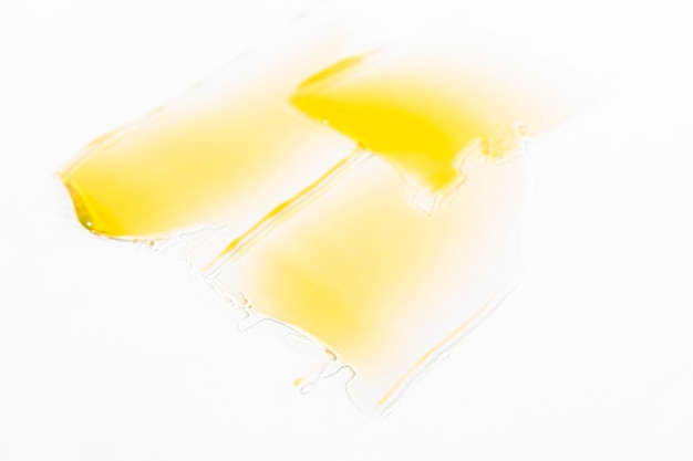 Smears of yellow liquid cosmetic product on a light gray background top view