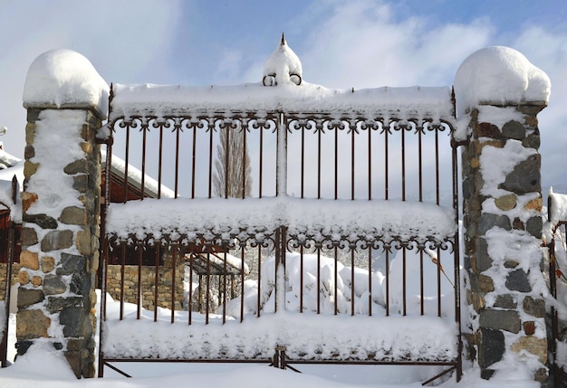 Smeedijzeren hek bedekt met sneeuw van een alpenhuis