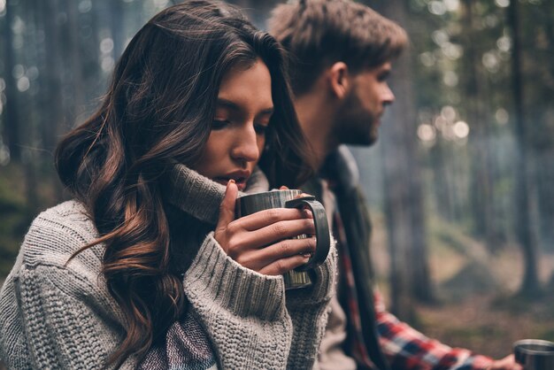 냄새가 너무 좋아요... 숲에 앉아 따뜻한 음료를 즐기는 젊은 아름다운 커플