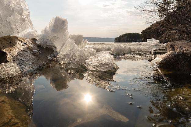 Foto smelten van ijs in het meer in de lente, weerspiegeling van ijs en de zon in het water, tijd vóór zonsondergang