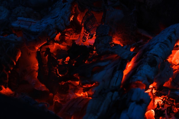 Smeulende houtblokken verbrand in levendig vuur close-up Sfeervolle achtergrond met vlam van kampvuur