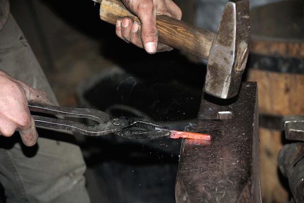 Smid bewerkt metaal met hamer op het aambeeld in de smidse