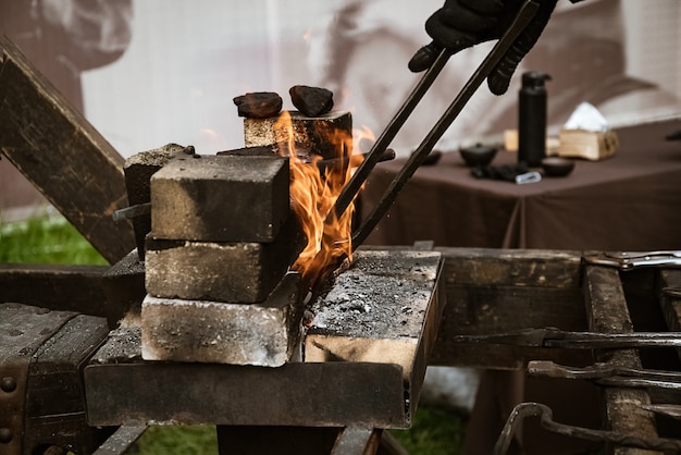 Smid haalt roodgloeiend metalen product met een tang uit het vuur