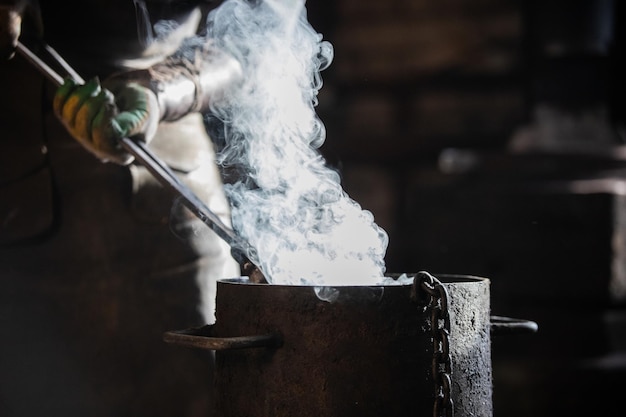 Smid koelt het detail af in een emmer gevuld met koud water