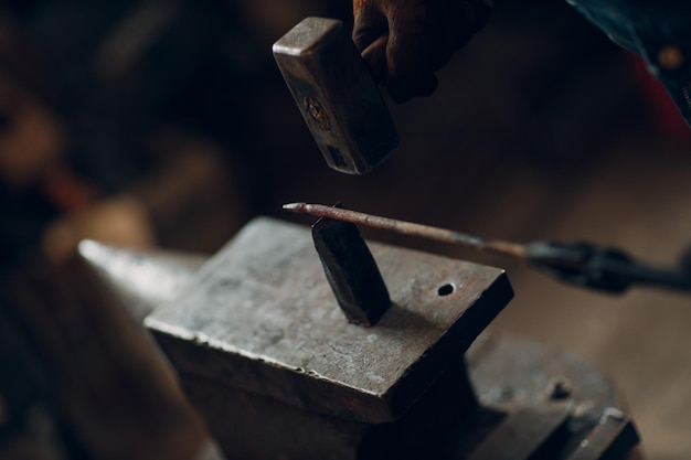 Smid smeedt en maakt metalen detail met hamer en aambeeld bij smederij