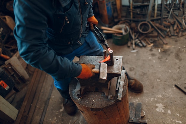 Smid smeedt en maakt metalen detail met hamer en aambeeld bij smederij