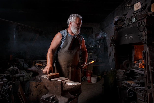 Smid vakman in schort werkt in de smidse