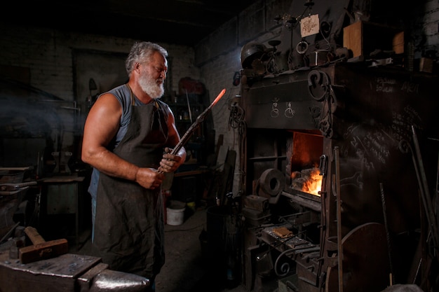 Smid vakman in schort werkt in de smidse