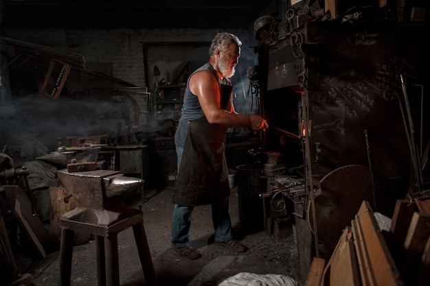 Smid vakman in schort werkt in de smidse