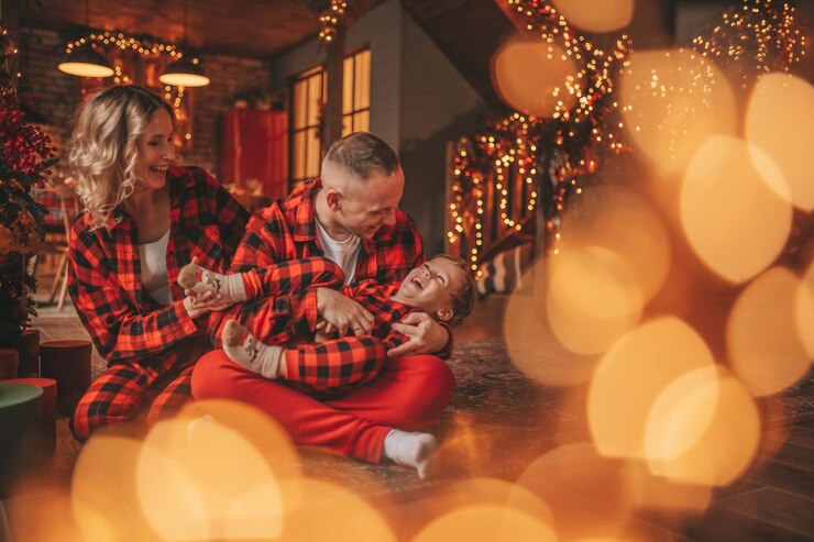 Photo smile active parents with small son in red checkered sleepwears waiting santa indoor