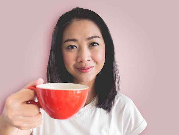 Smile Asian woman is drinking coffee from red cup.