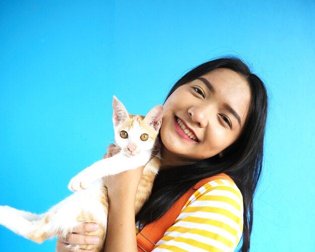 Smile beautiful girl with lovely cat on blue background.