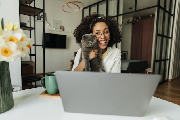 Smile black woman looking at laptop with cat at home