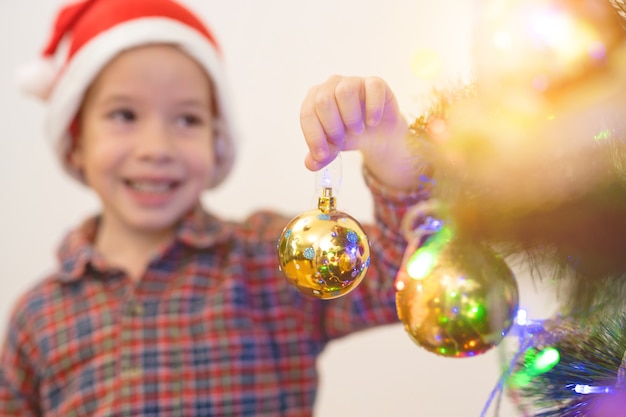 The smile boy hold a glass ball near the christmas tree