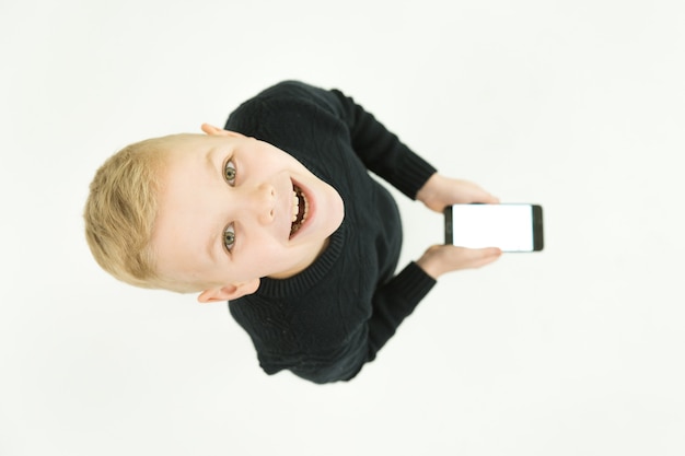 笑顔の少年はスマートフォンを持って立っています。上から見る