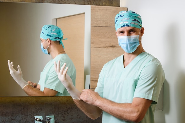 Smile chirurg zet steriele medische handschoenen op zijn handen en kijkt naar de voorkant