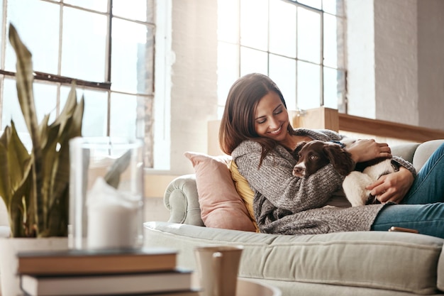 Foto sorridi cane e donna su un divano rilassati e ama con gioia giocoso e spensierato a casa persona femminile ragazza e signora su un divano animale domestico e felicità su un divano libertà e rottura con un animale domestico