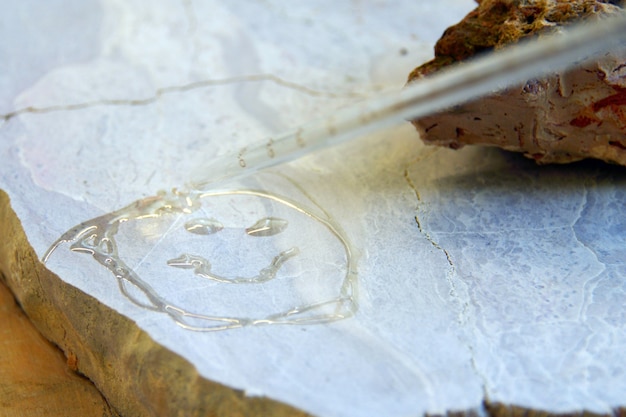 Photo smile emoticon painted bywater on the stone, wet stones. geology concept and testing with chloride at laboratory