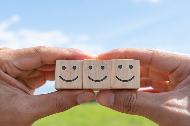 Foto smile face e icona del carrello sul cubo di legno. persona o persone ottimiste che si sentono dentro e valutazione del servizio durante lo shopping, concetto di soddisfazione negli affari.