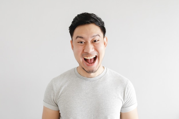 Smile face of happy man wear grey t-shirt and on grey wall.