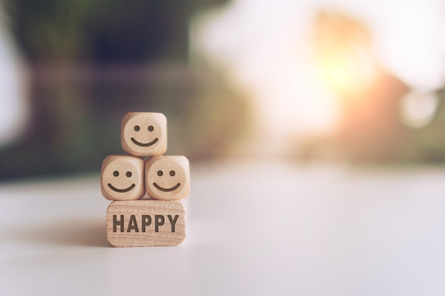 Smile face and Happy word on wooden cube. Optimistic person or people feeling inside.