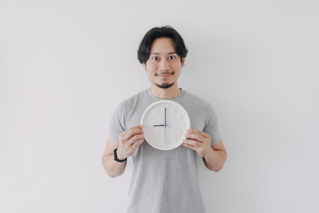 Smile face man in grey tshirt holding a white clock concept of time