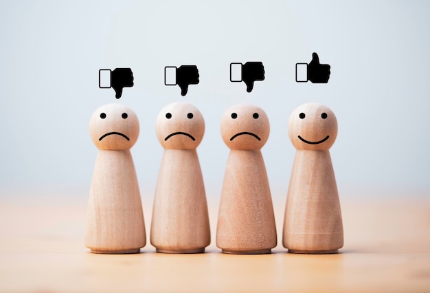 Smile face print screen on wooden figure among sadness figures for customer service evaluation and emotion mindset concept.